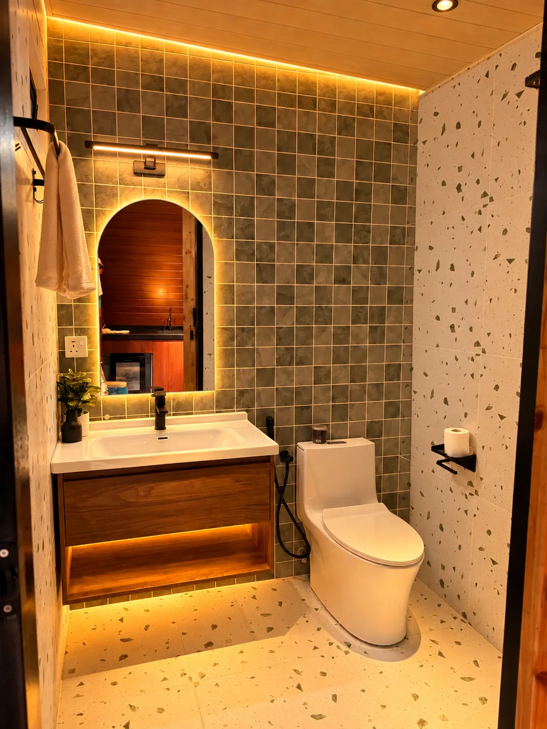 Resort bathroom with an illuminated mirror and warm tiled finishes